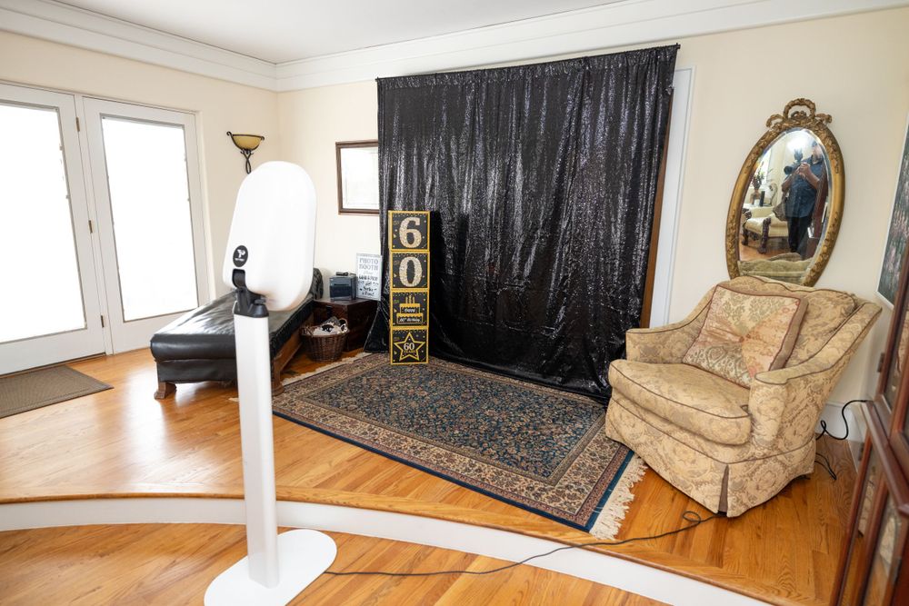 Living room setup with black backdrop, ornate mirror, and comfortable armchair on hardwood floors.