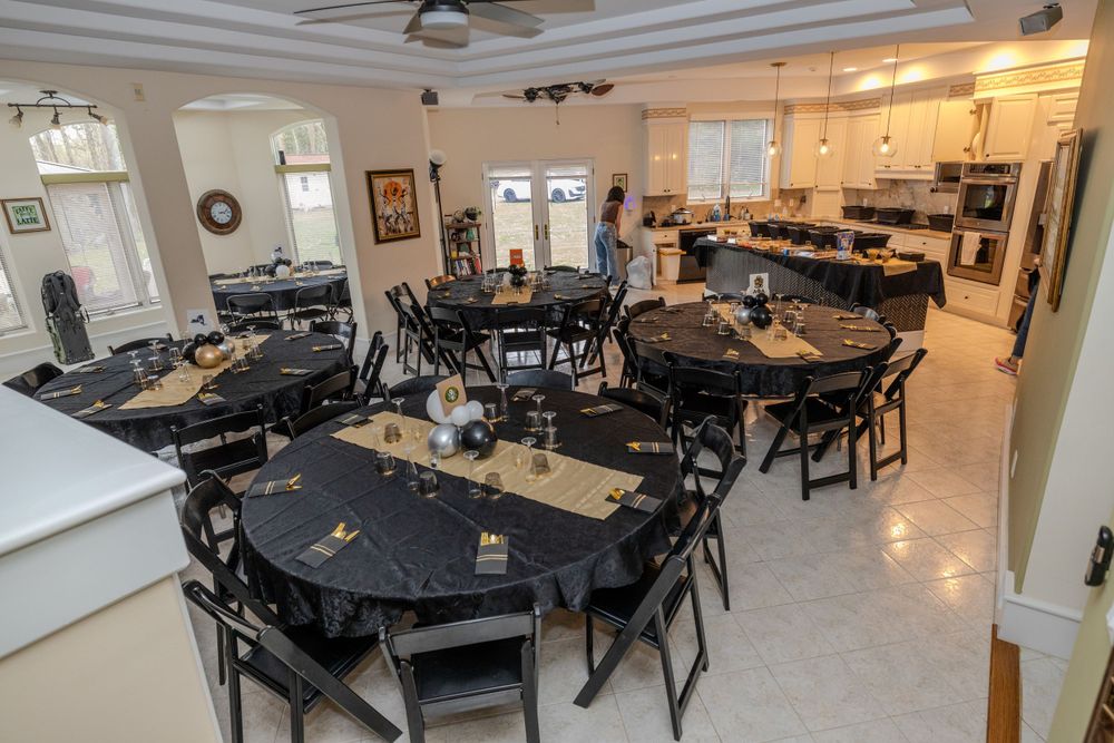 Spacious dining area with multiple round tables and black chairs set for an event.