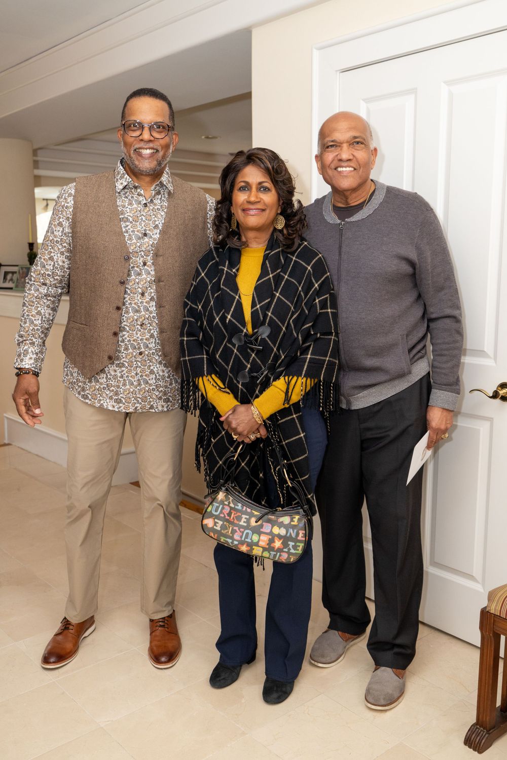 Warm gathering of individuals in casual attire standing together in a home setting.