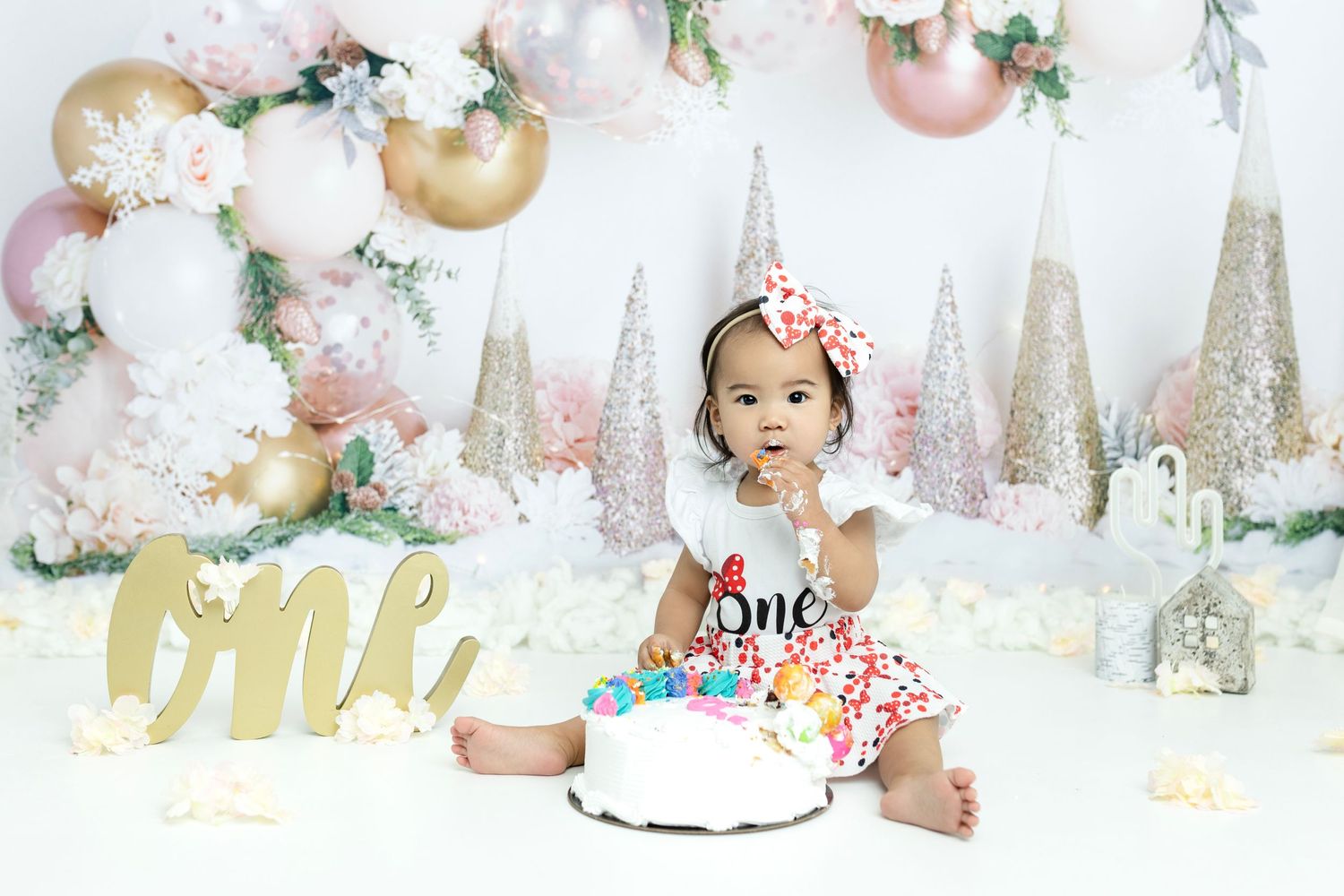 Winter wonderland themed cake smash setup with pink and gold accents.
