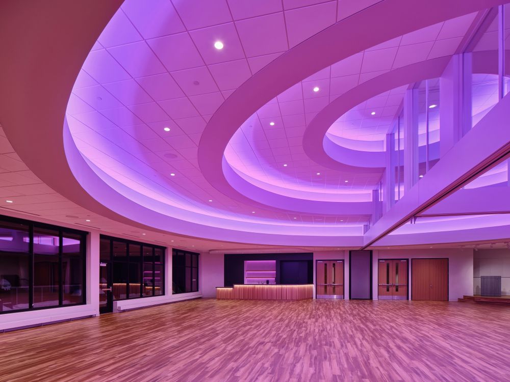 Event space with purple LED lighting illuminating a curved ceiling design above hardwood floors.