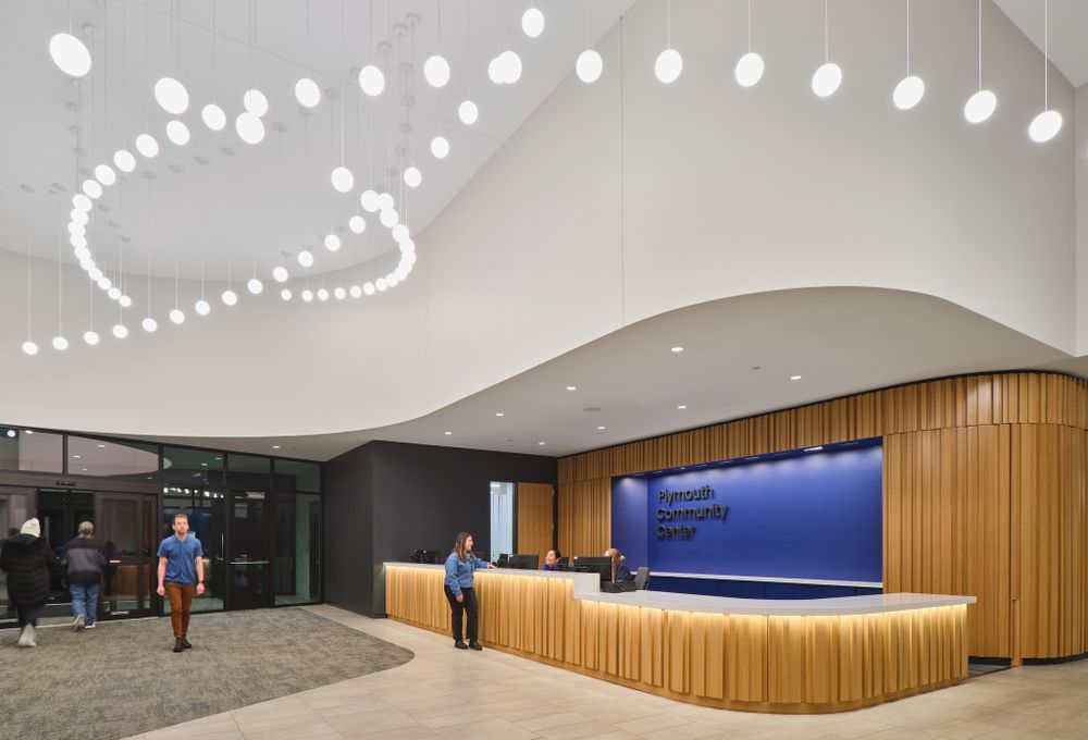 Contemporary lobby featuring wooden reception desk and artistic dot pattern lighting installation.