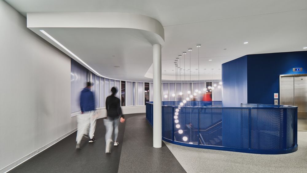 Sleek office corridor with curved blue reception counter and white dot lighting pattern.