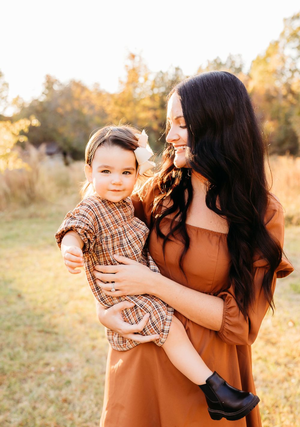 A heartwarming outdoor family photoshoot at golden hour showing tender embraces and joyful moments in a field.