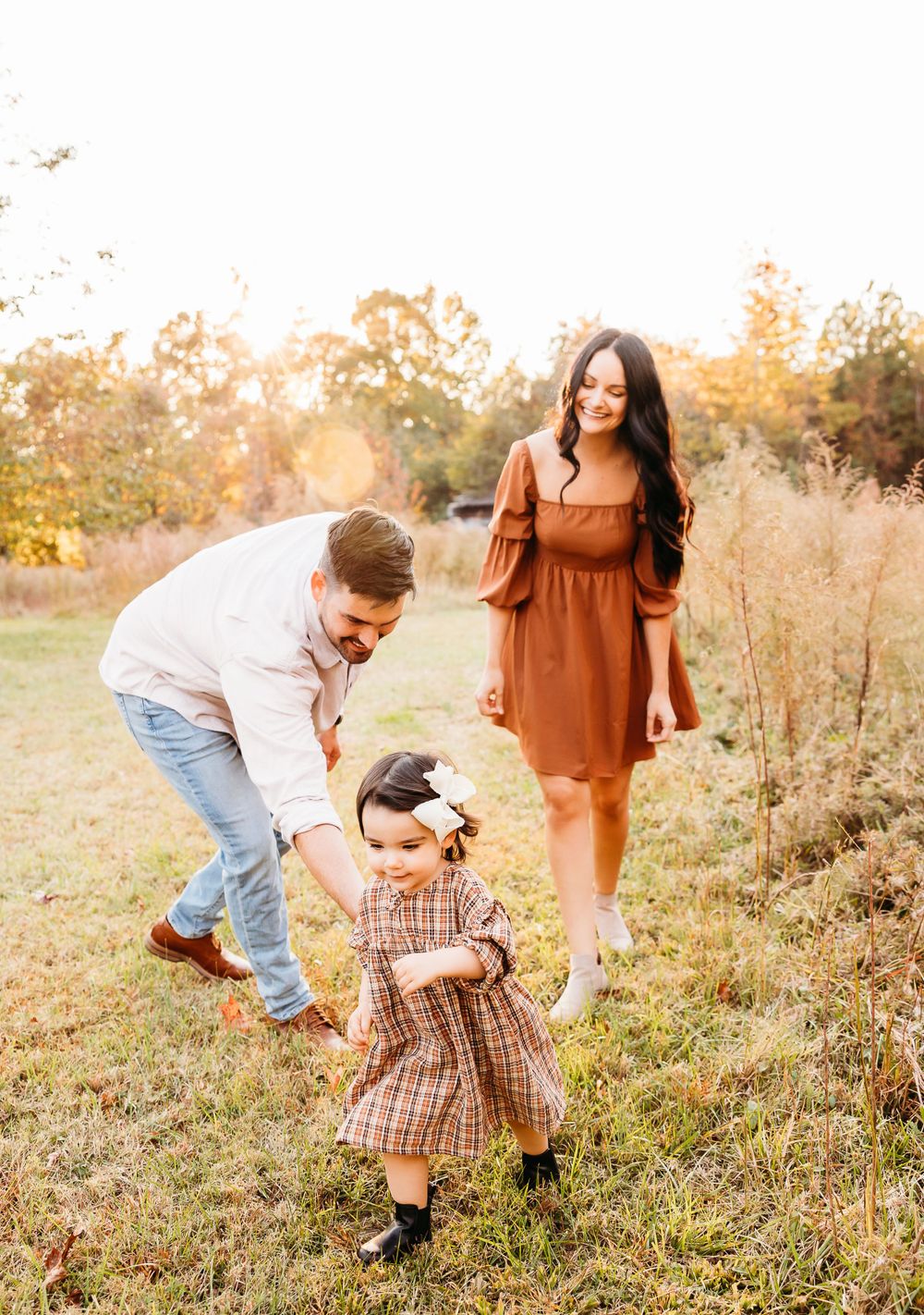 A family plays together in a golden autumn field during sunset, creating candid moments in warm earth tones.