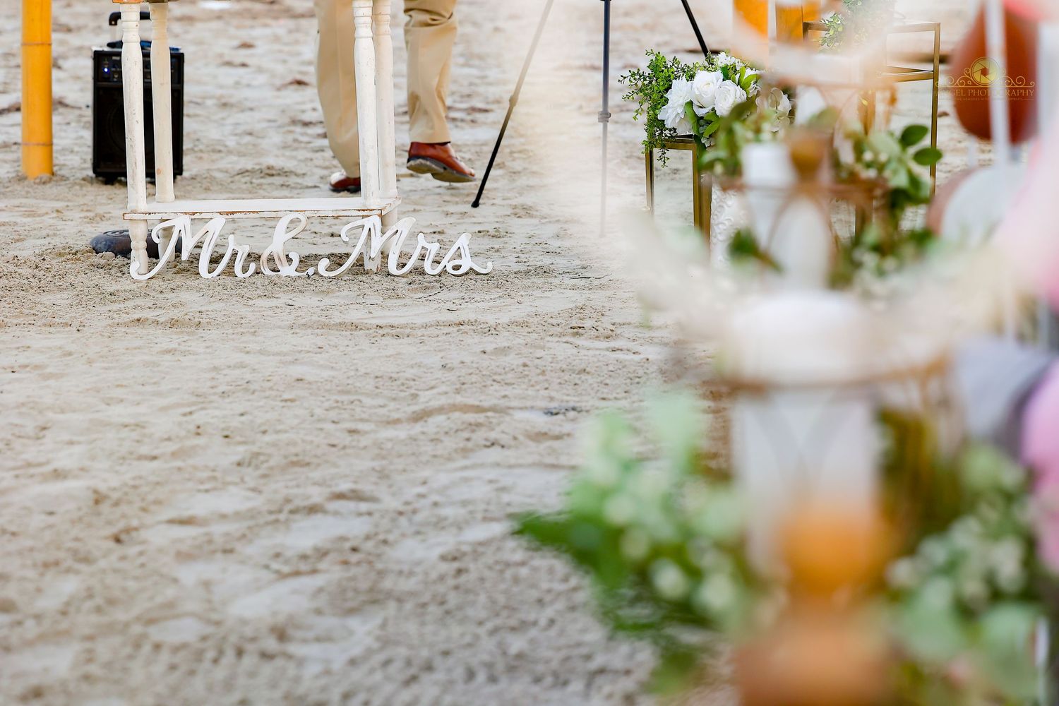 Decorative Mr and Mrs text sign displayed on rustic wooden surface with blurred floral decor.