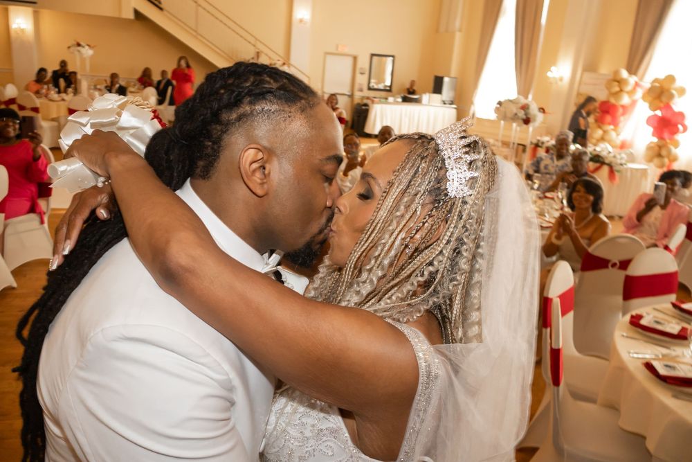 Newlywed couple sharing a romantic first kiss at their wedding reception in an elegant ballroom.
