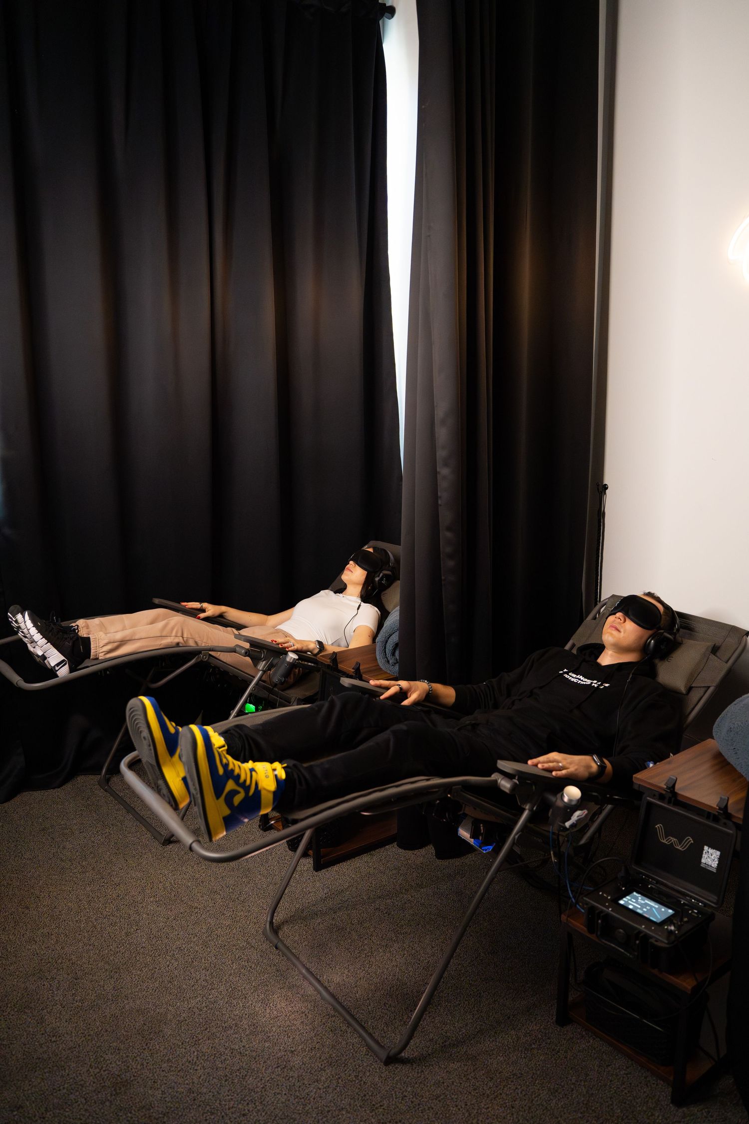Two people reclined in lounge chairs wearing VR headsets in a dark room.