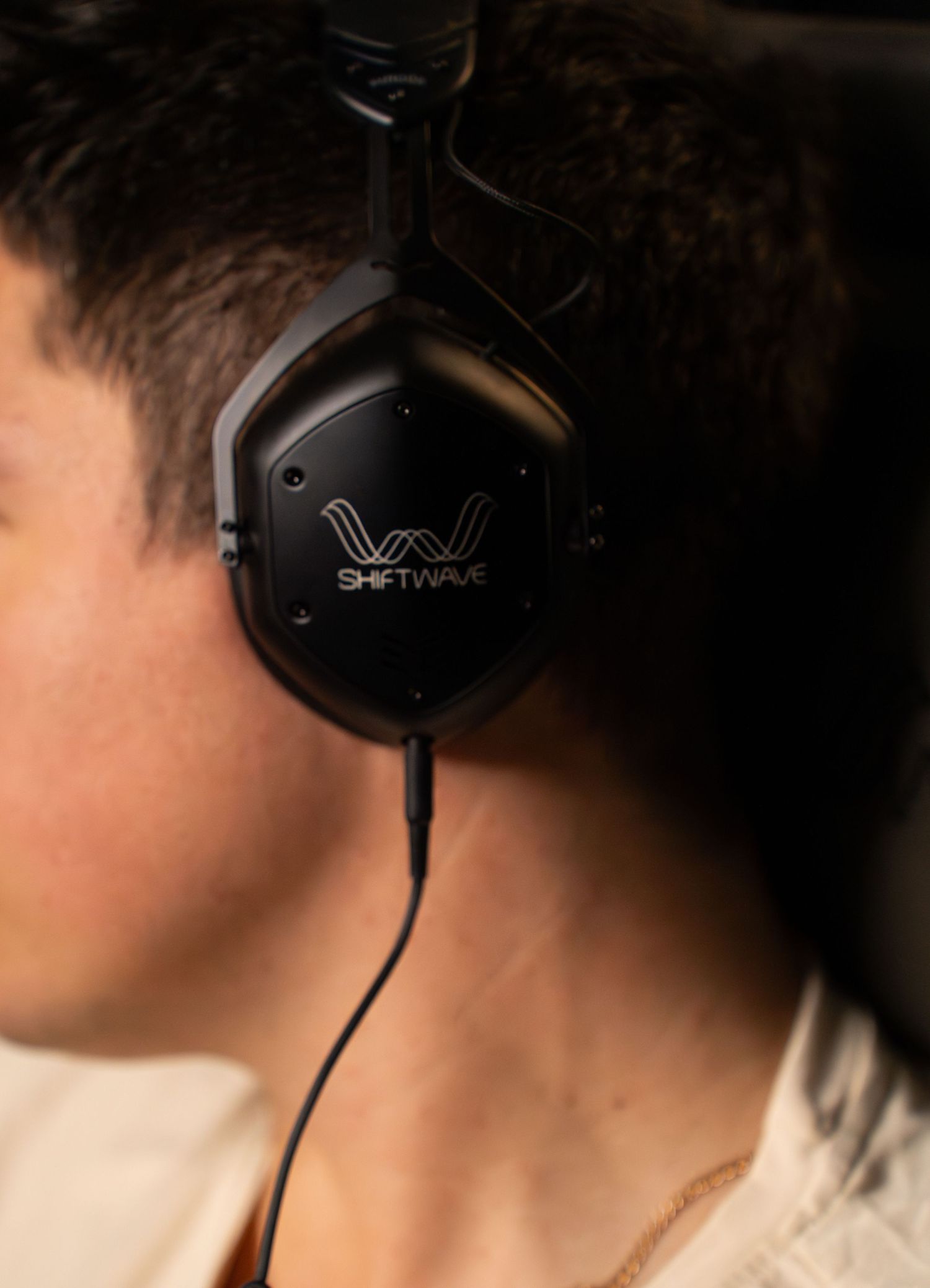 Close-up of Wave-branded black headphones being worn.