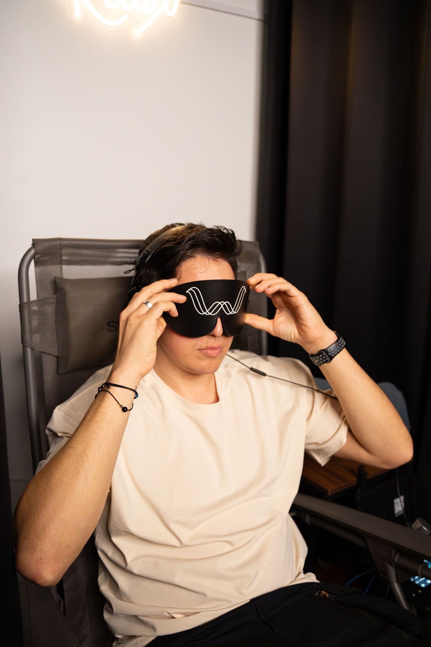 Someone wearing virtual reality goggles with a Wave logo while sitting in a chair.