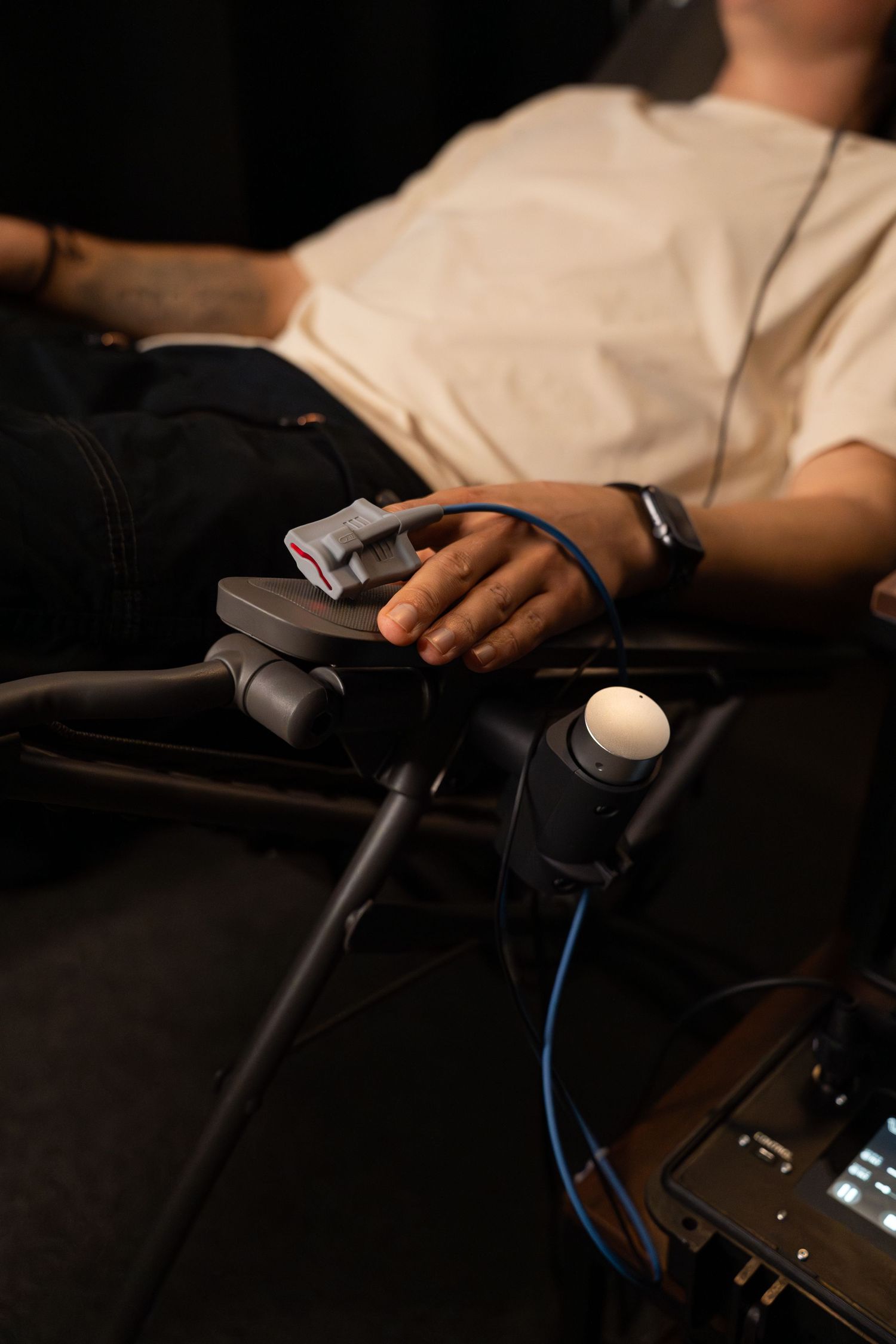 Hand resting on gaming controller with headphone cable visible in low light setting.