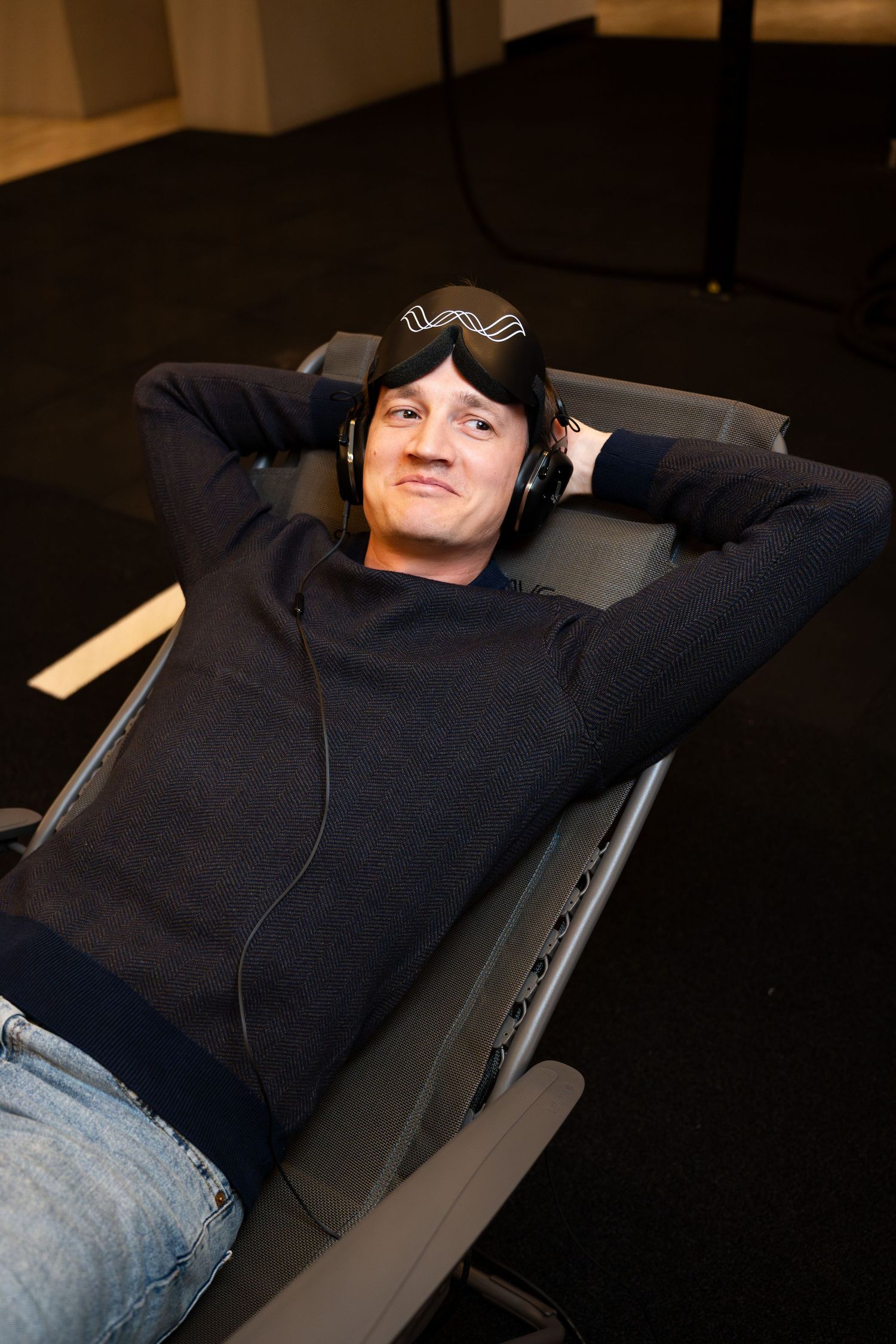 Client relaxing in reclined position while wearing headphones and sleep mask.
