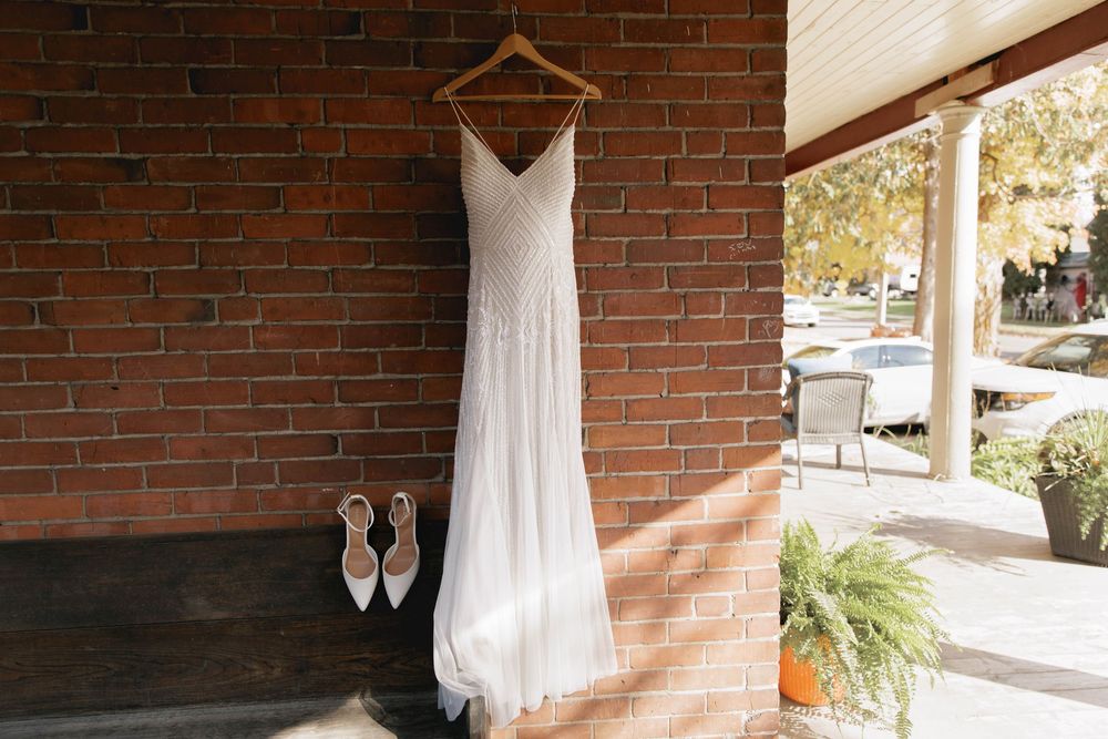 A series of wedding preparation photos showing white dresses hanging against brick walls in natural sunlight.