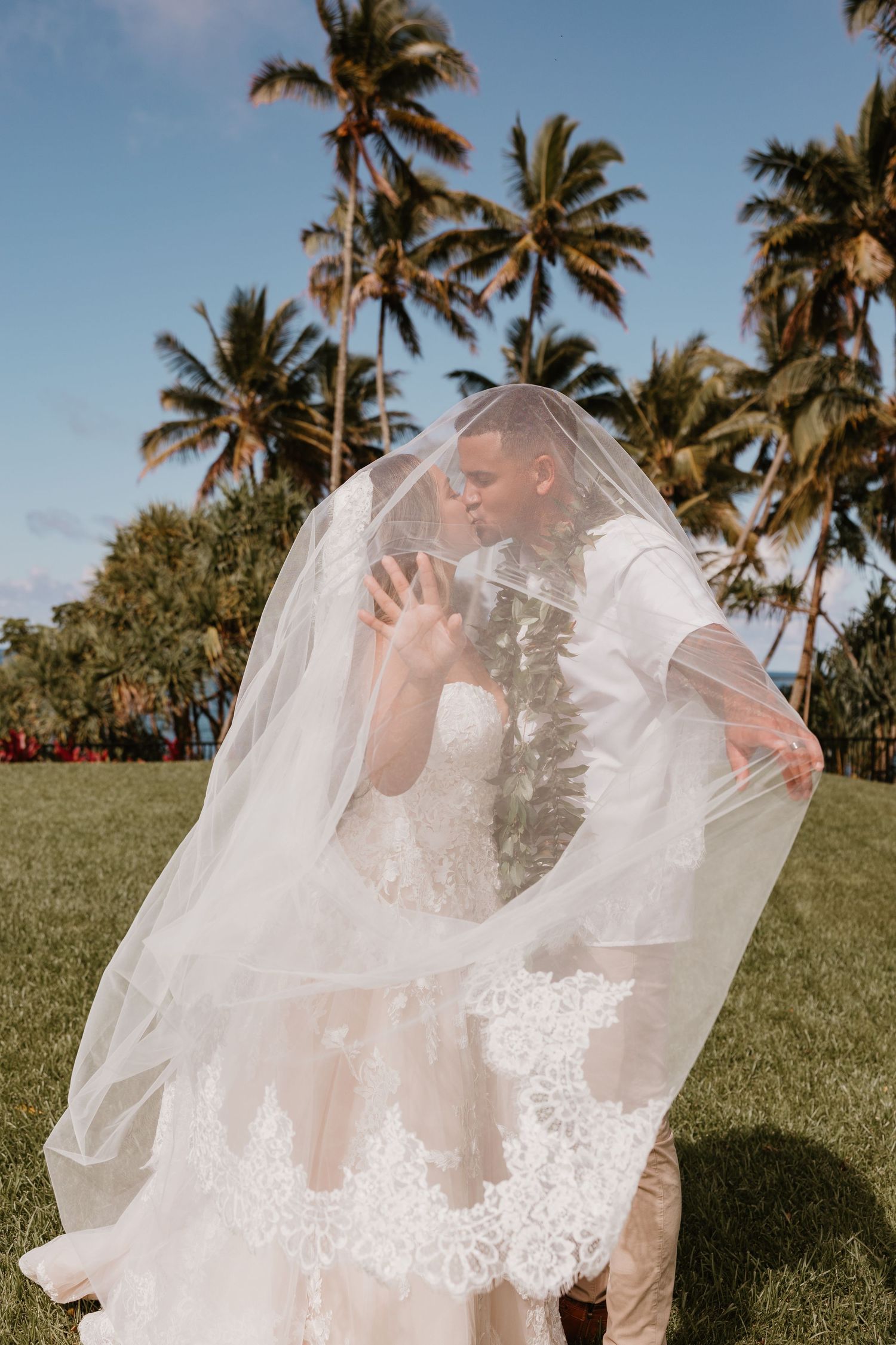 Wedding couple intimate elopement daughter carrying train sunset on beach hawaii waikoloa big island first kiss tropical bouquet
