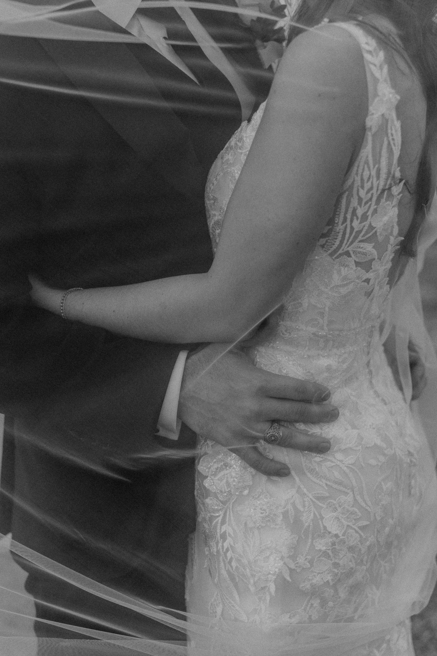 Black and white close-up of couple embracing in formal wedding attire.