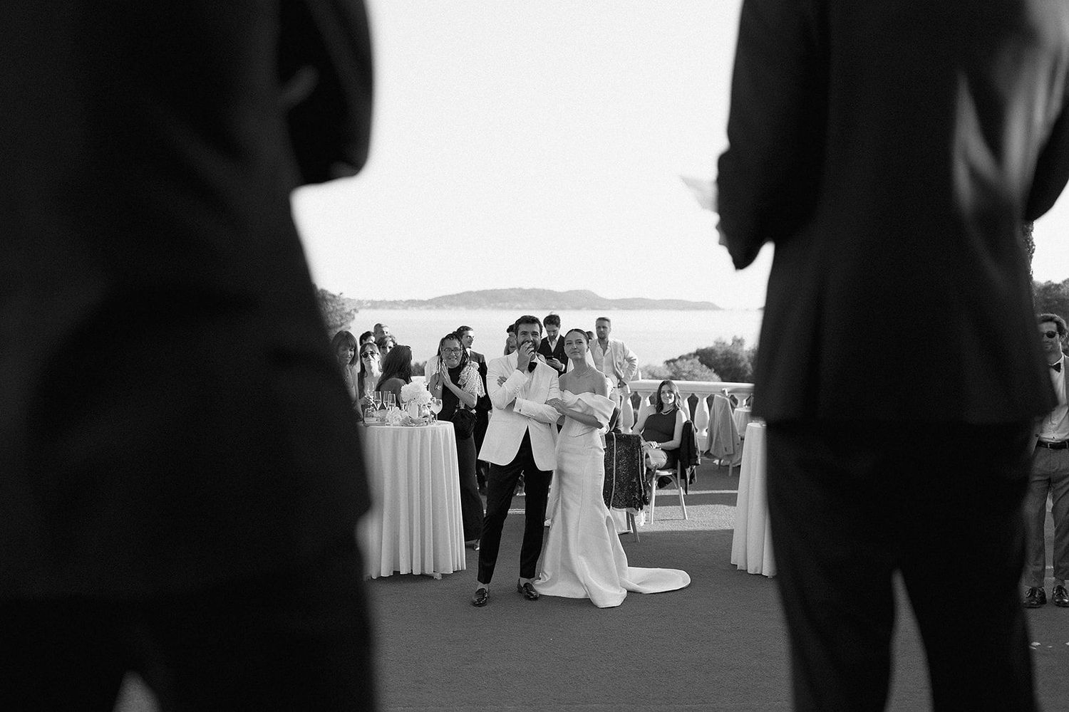 Black and white wedding portrait on a hillside overlooking water and trees.
