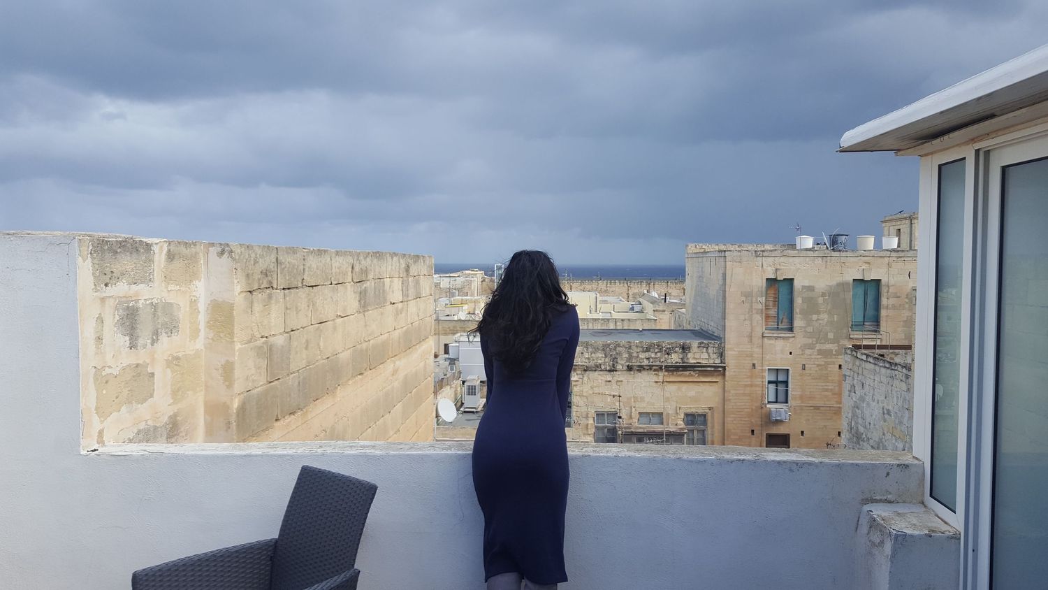 Panoramic rooftop view of a cloudy cityscape with modern buildings.