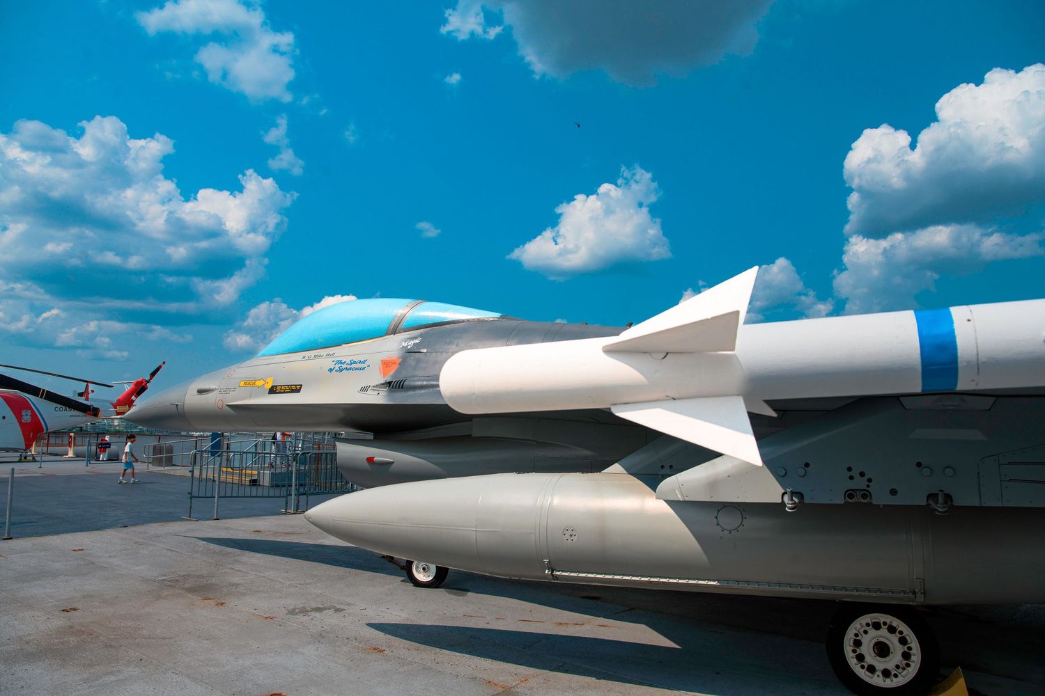 Close-up view of missiles mounted under the wing of a military aircraft against blue sky.