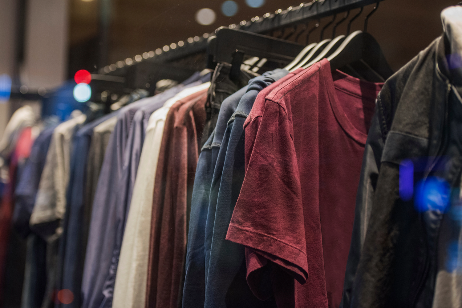 Rack of colorful clothing on hangers in retail store display.