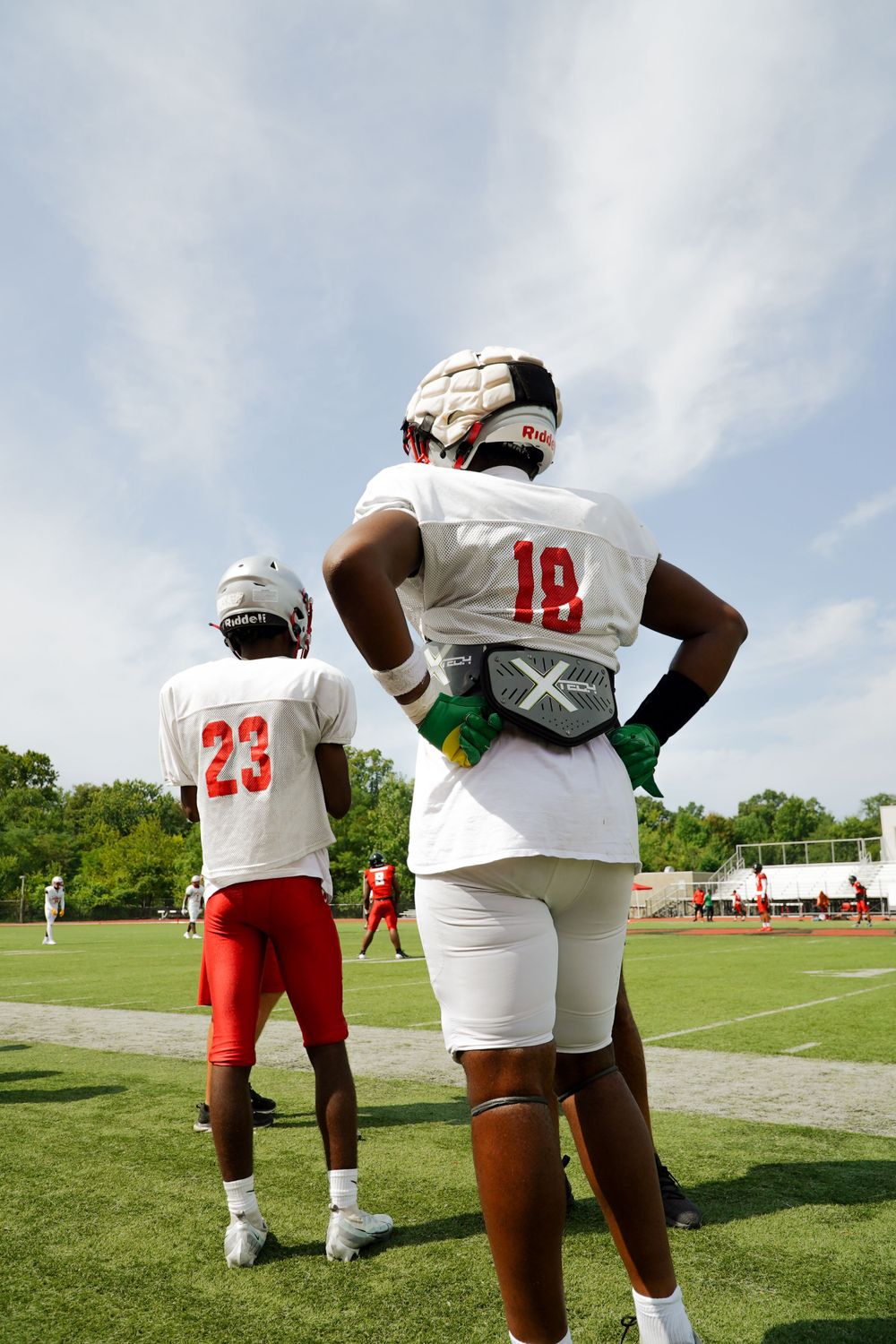 Two football players in white and red uniforms standing on practice field during training.