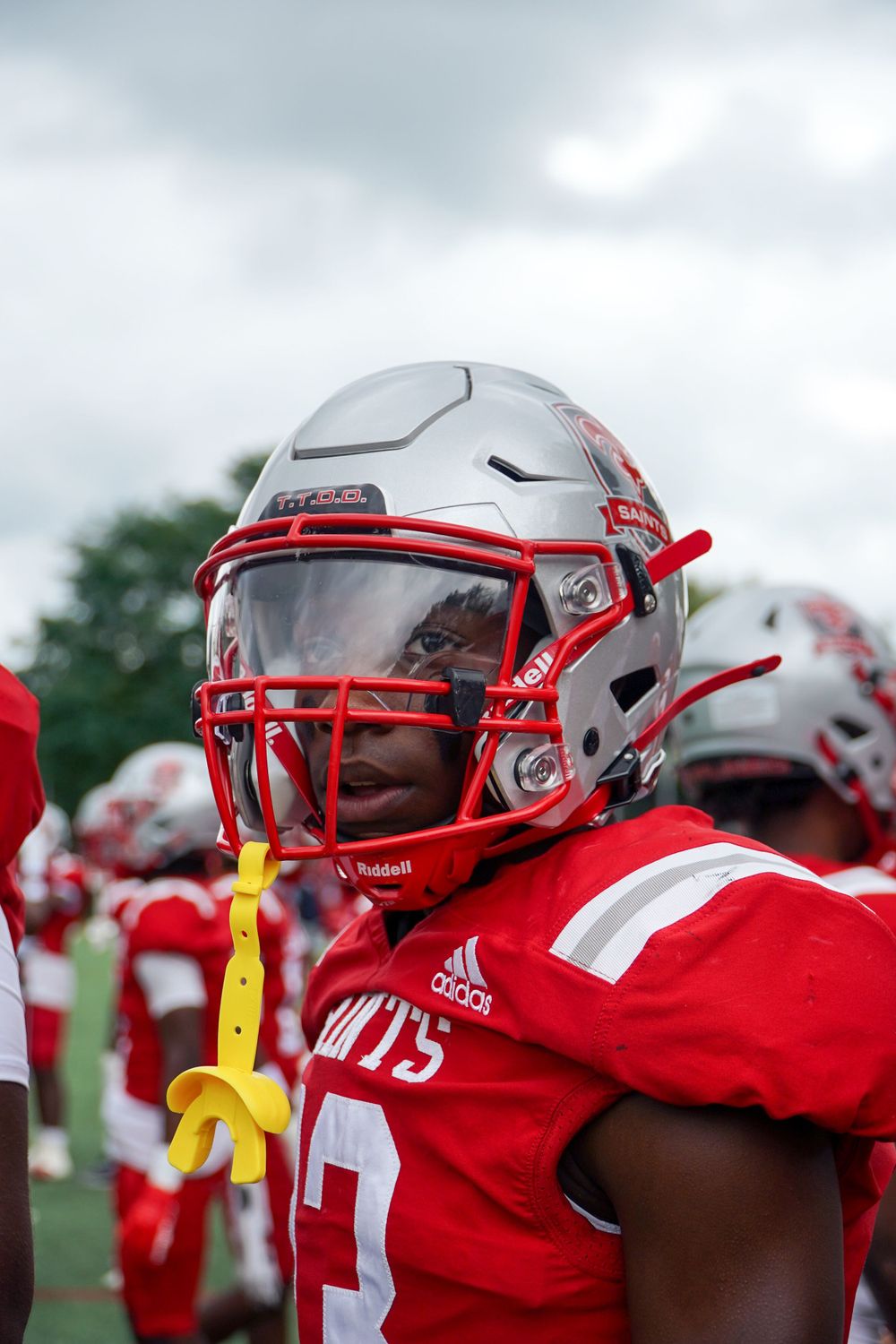 Close-up shot of football player in red uniform wearing white protective helmet with face guard.