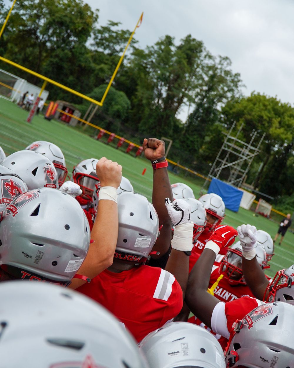 Team huddle of football players in red and white uniforms with raised fists showing team spirit.