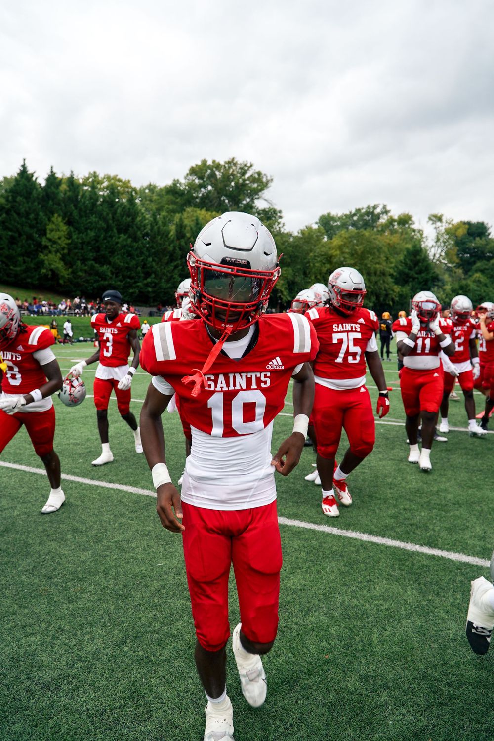 Football player in red Saints uniform number 10 on field during pregame warmup.