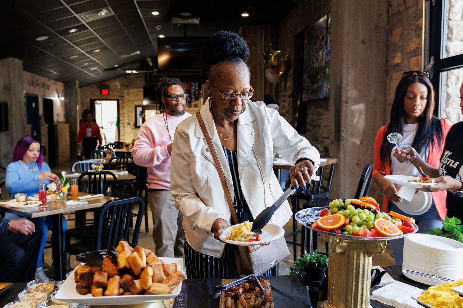 Chef prepares food at buffet table in restaurant setting.