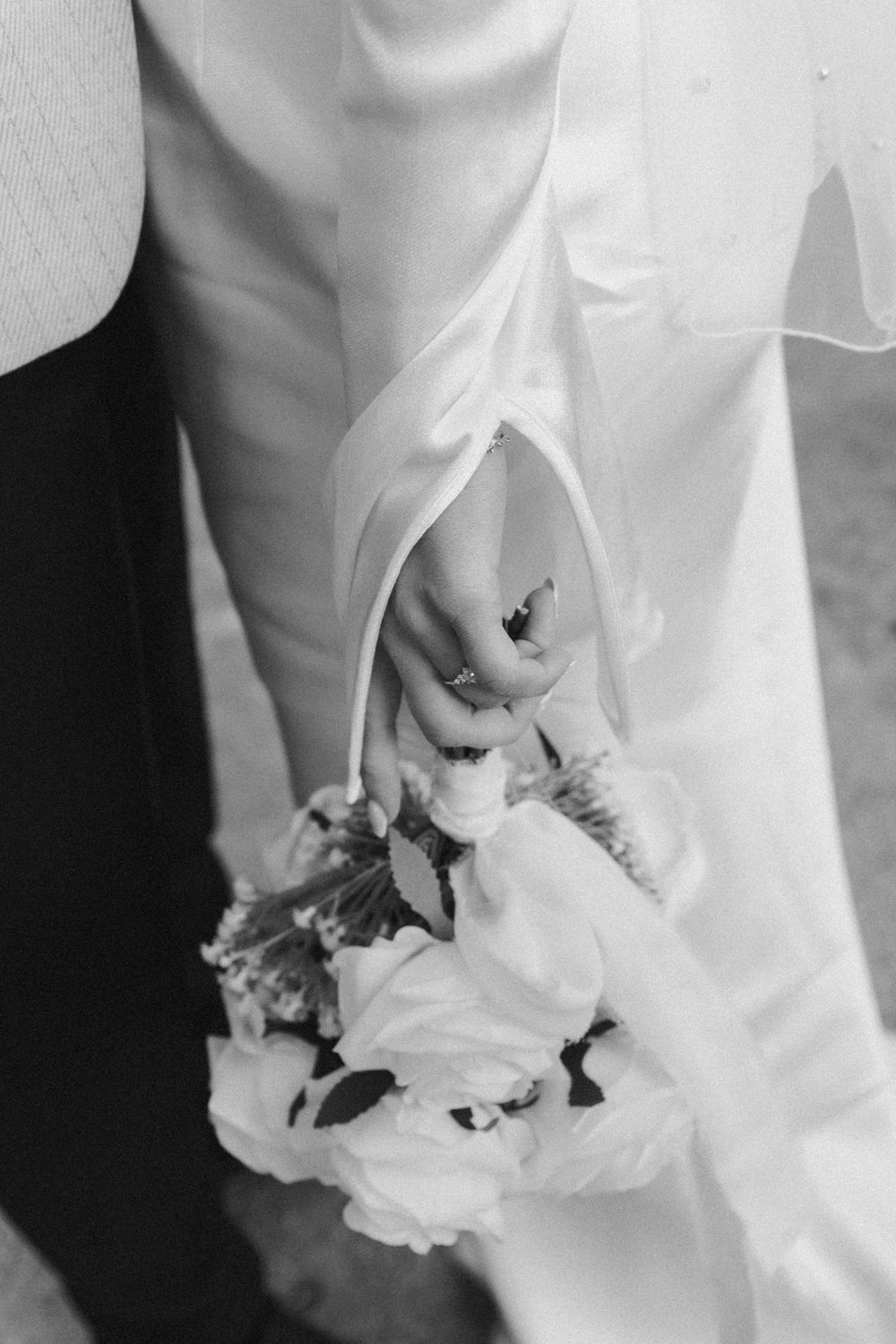 Close-up details of white wedding dress fabric being held with delicate fingers.