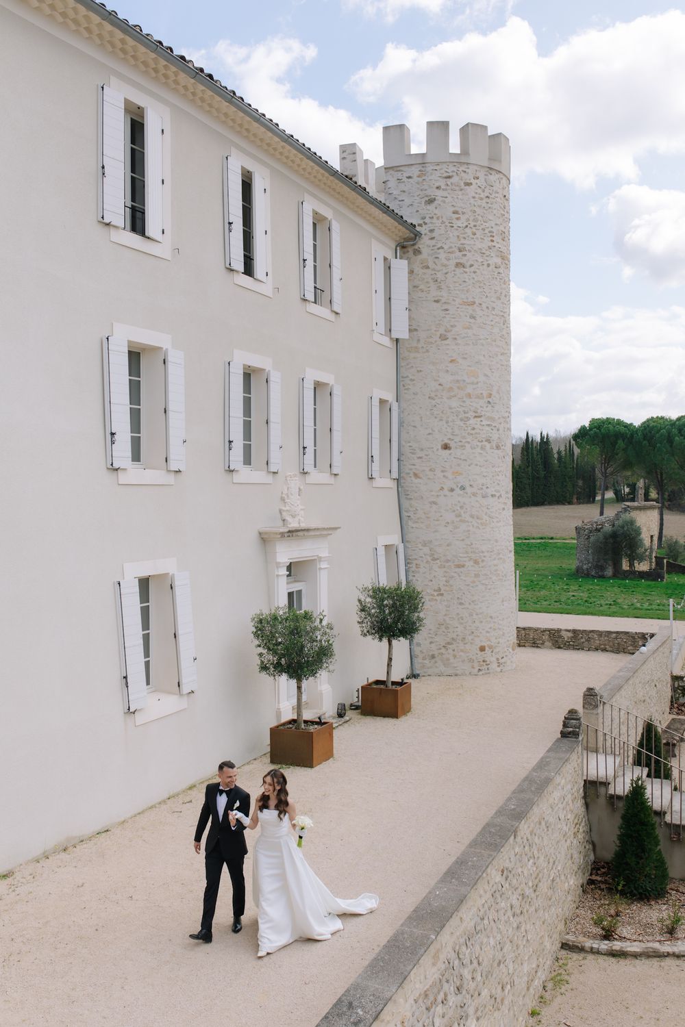 A series of minimalist white stone buildings with windows and architectural details at a French chateau venue.