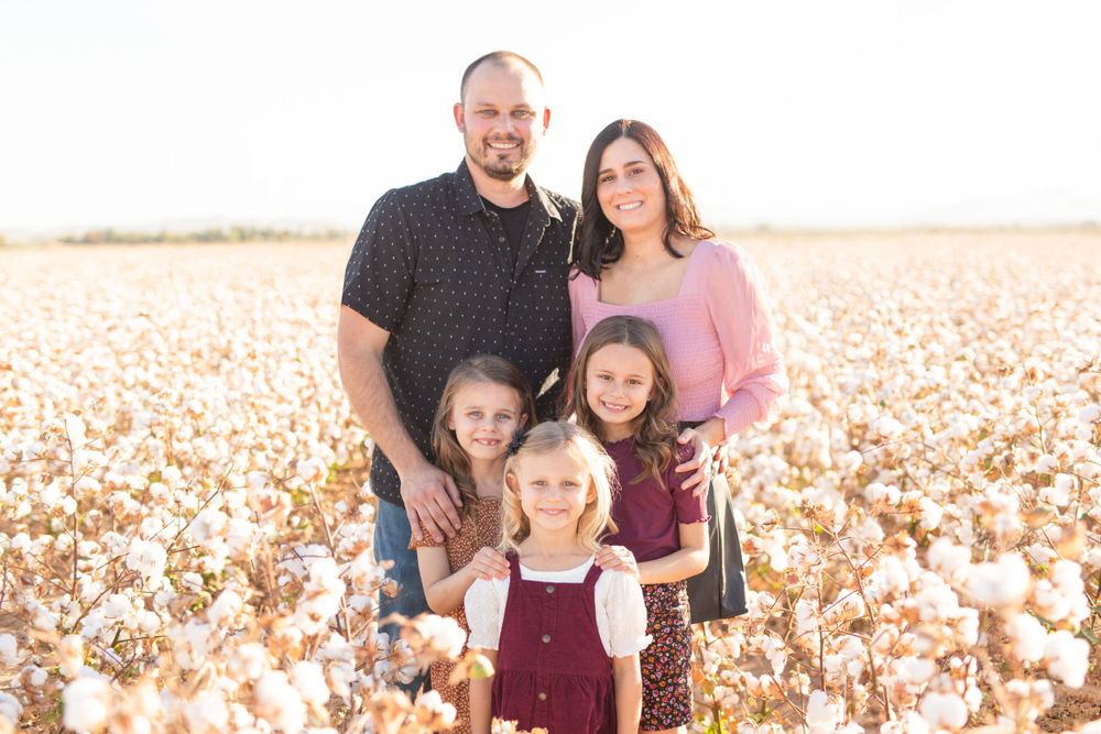 A family portrait taken in a cotton field during golden hour.