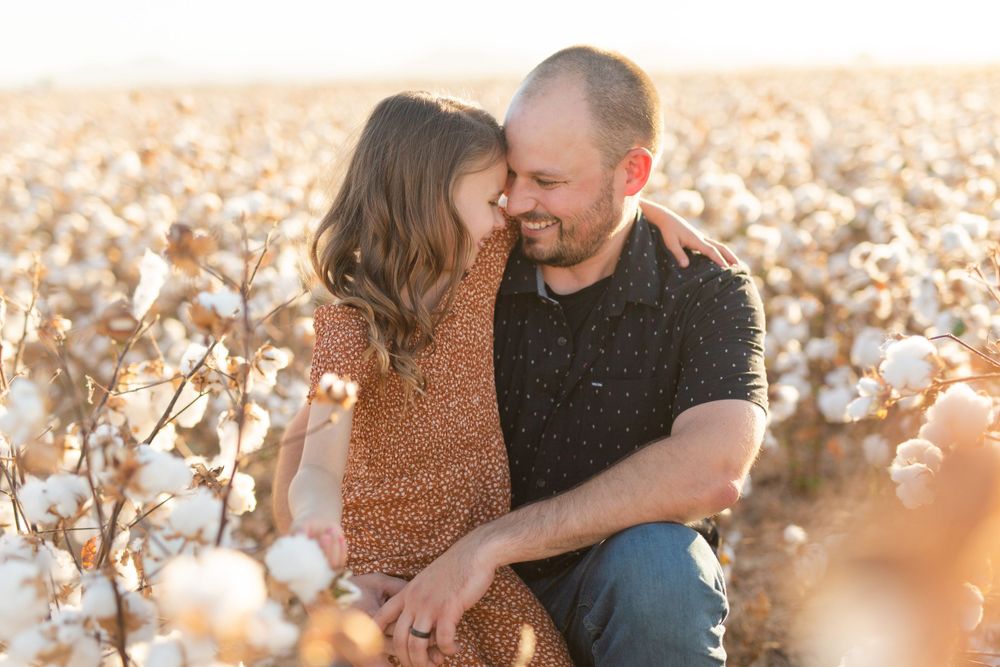 An intimate moment shared between two people in a cotton field at sunset.