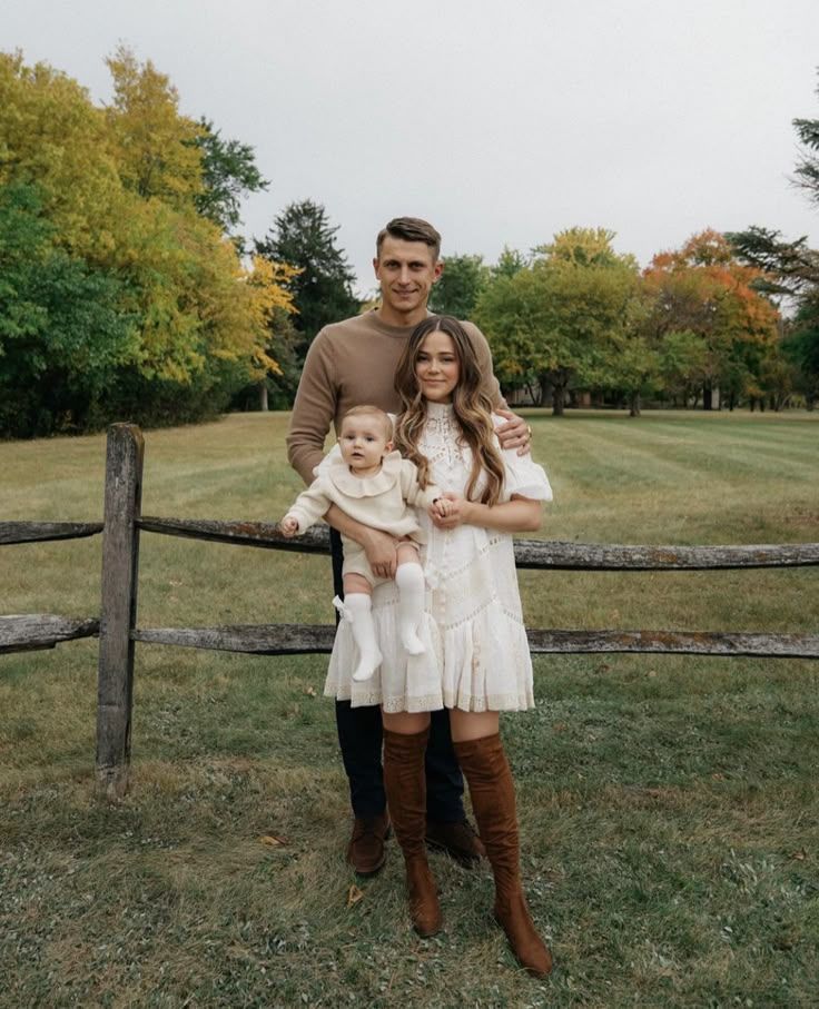 Outdoor family portrait series with rustic fence backdrop during golden autumn.