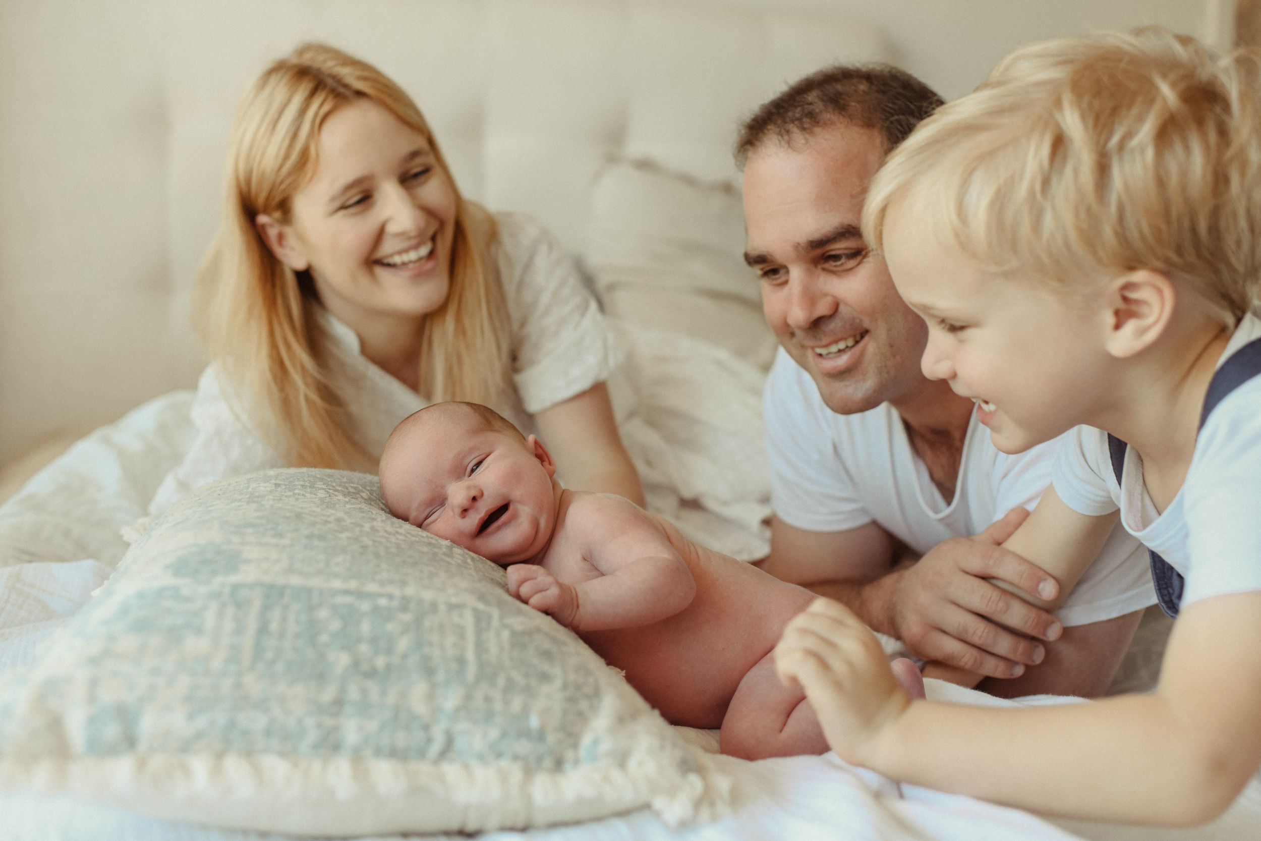 A family shares a tender moment together on a bed with a newborn.