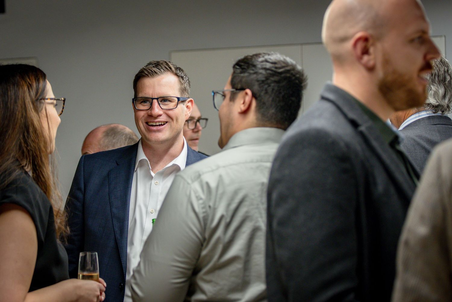 Professionals networking at a corporate event, smiling and engaging in conversation in a modern venue.