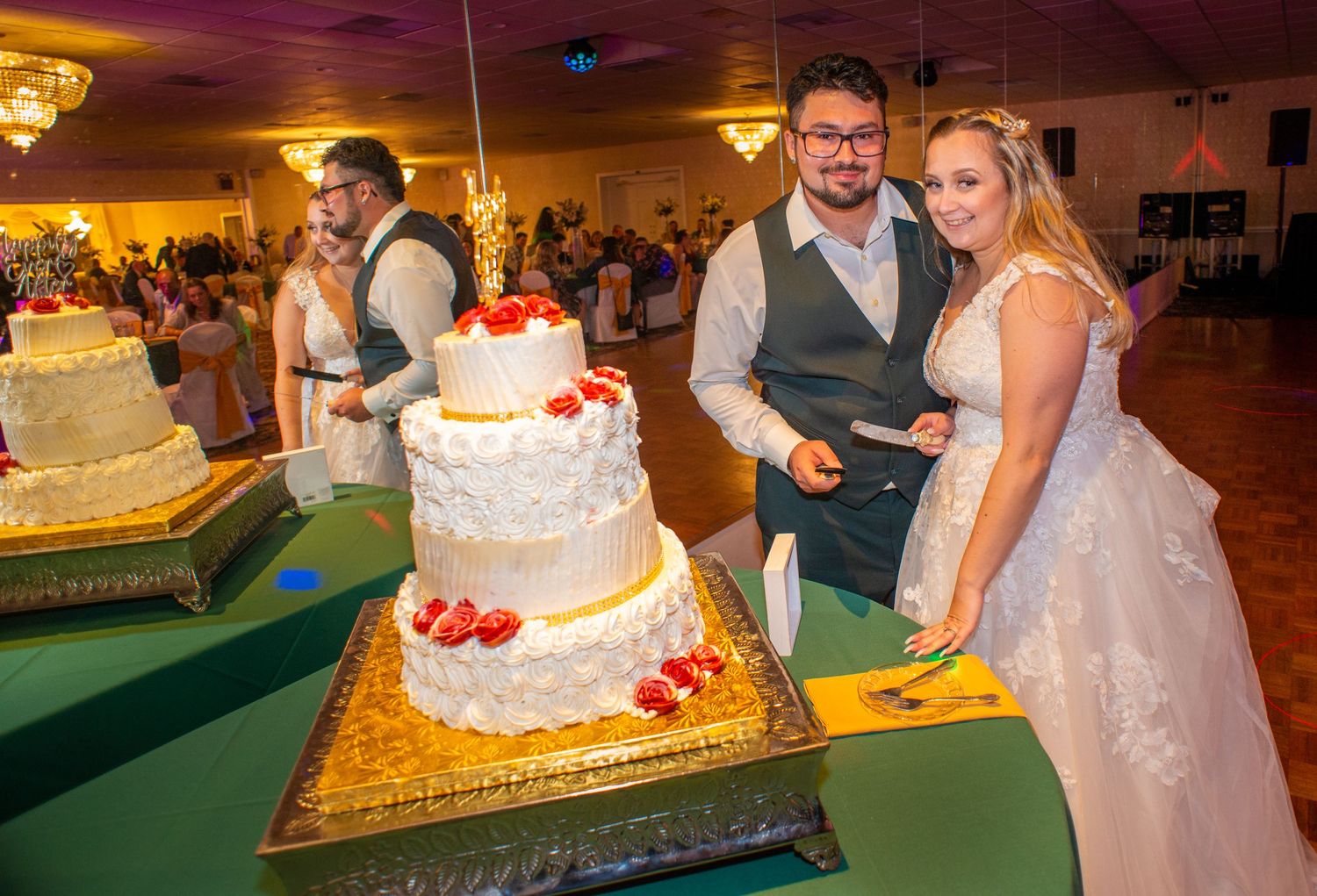 A wedding reception featuring an elegant multi-tiered white cake with red accents.