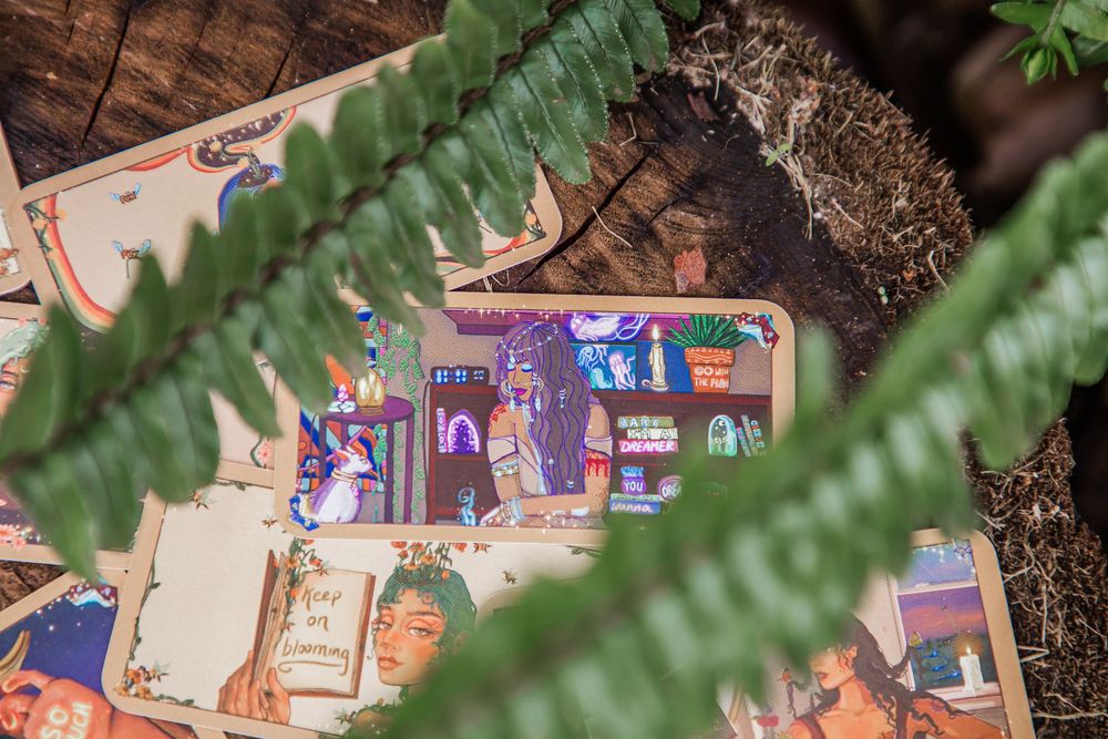 A collection of children's books and toys arranged on a wooden surface with green fern leaves in the background.