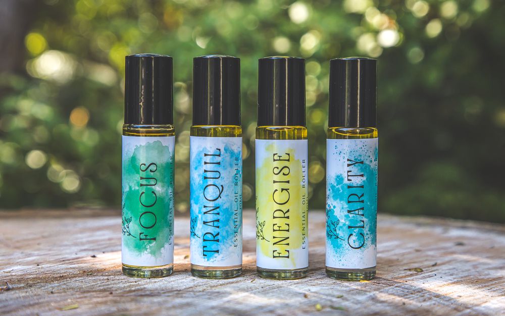 Four blue and green nail polish bottles arranged in a line on a rustic wooden surface with bokeh background.