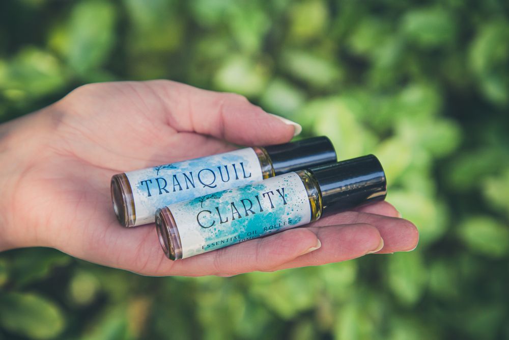 Essential oil roller bottles with blue labels displayed against green foliage background.