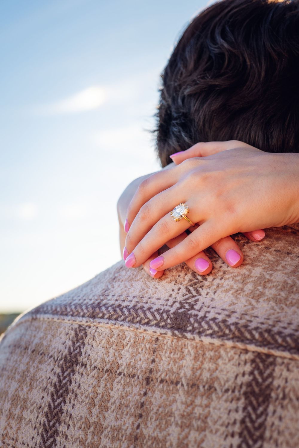 Close up of hands with pink nail polish resting on a knit sweater.
