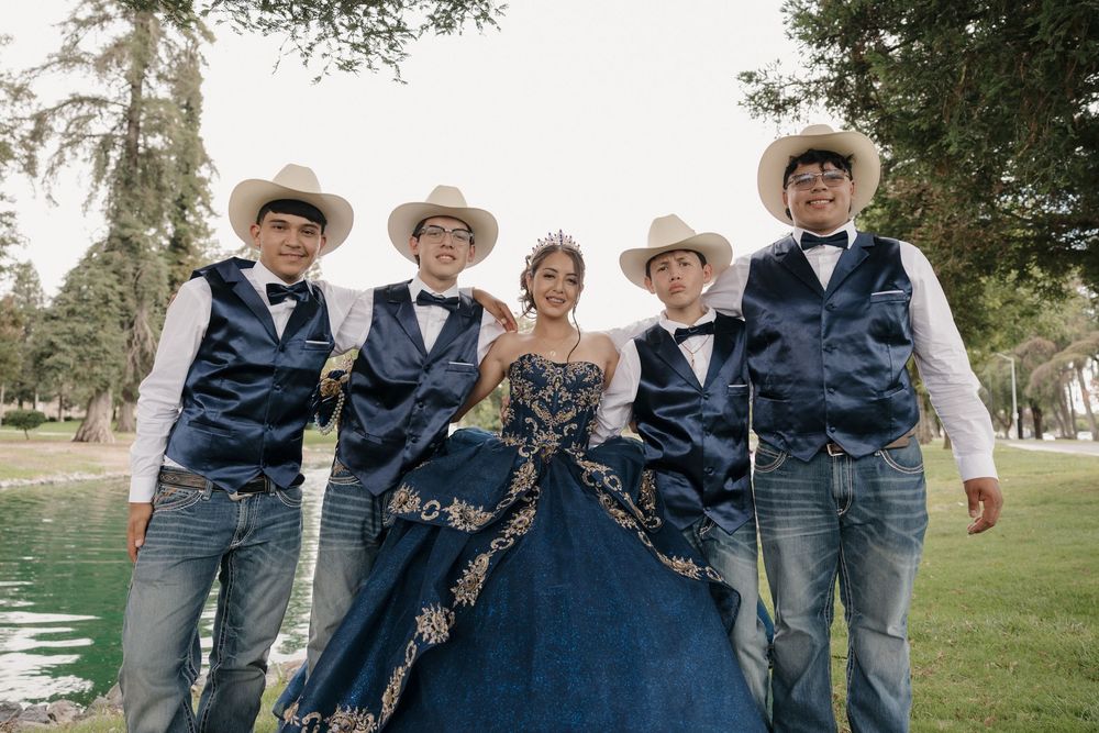 A group in blue wedding attire poses outdoors during a country themed celebration in a casual yet elegant setting.