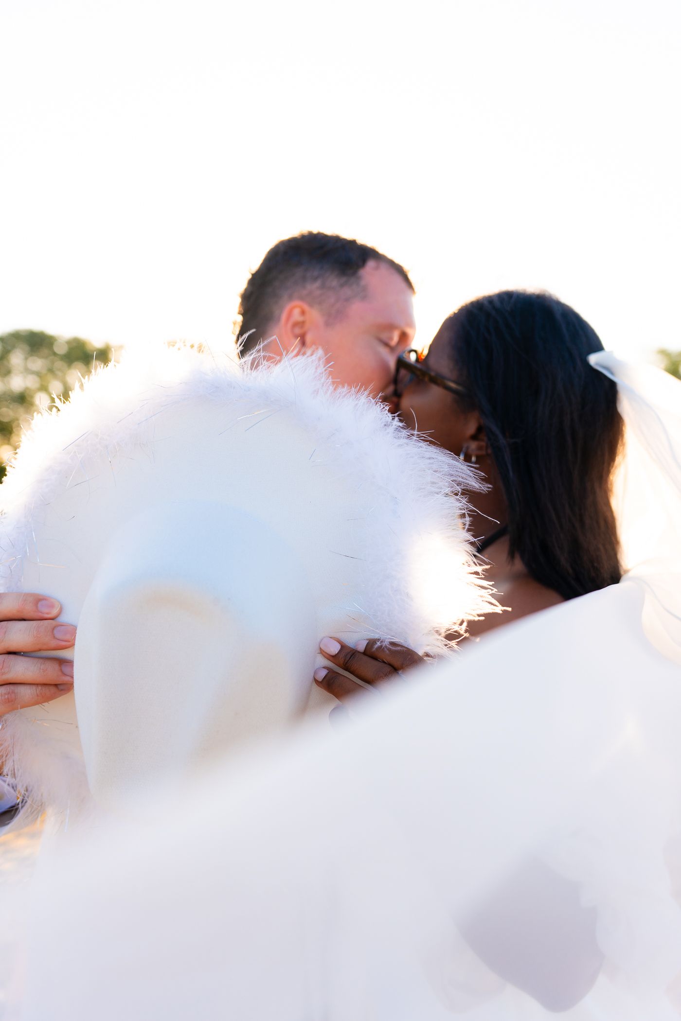 Romantic wedding couple embracing in soft sunlight with flowing veil.
