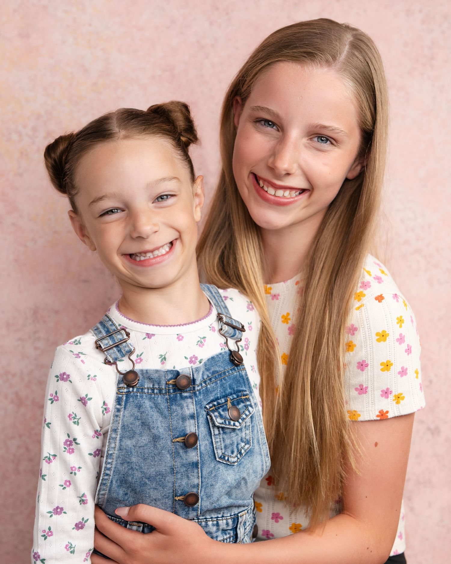 Two children wearing matching rainbow striped outfits pose together for a studio portrait in Guildford, Surrey.