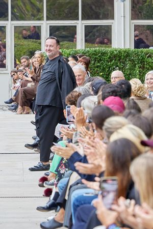 Fashion show audience seated along outdoor runway watching presentation.