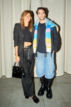Fashionable couple posing against white backdrop, wearing casual urban styles.