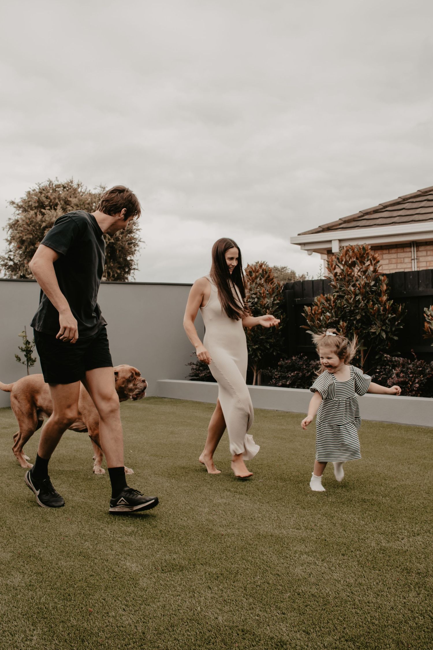 Family and their dog running in their backyard.