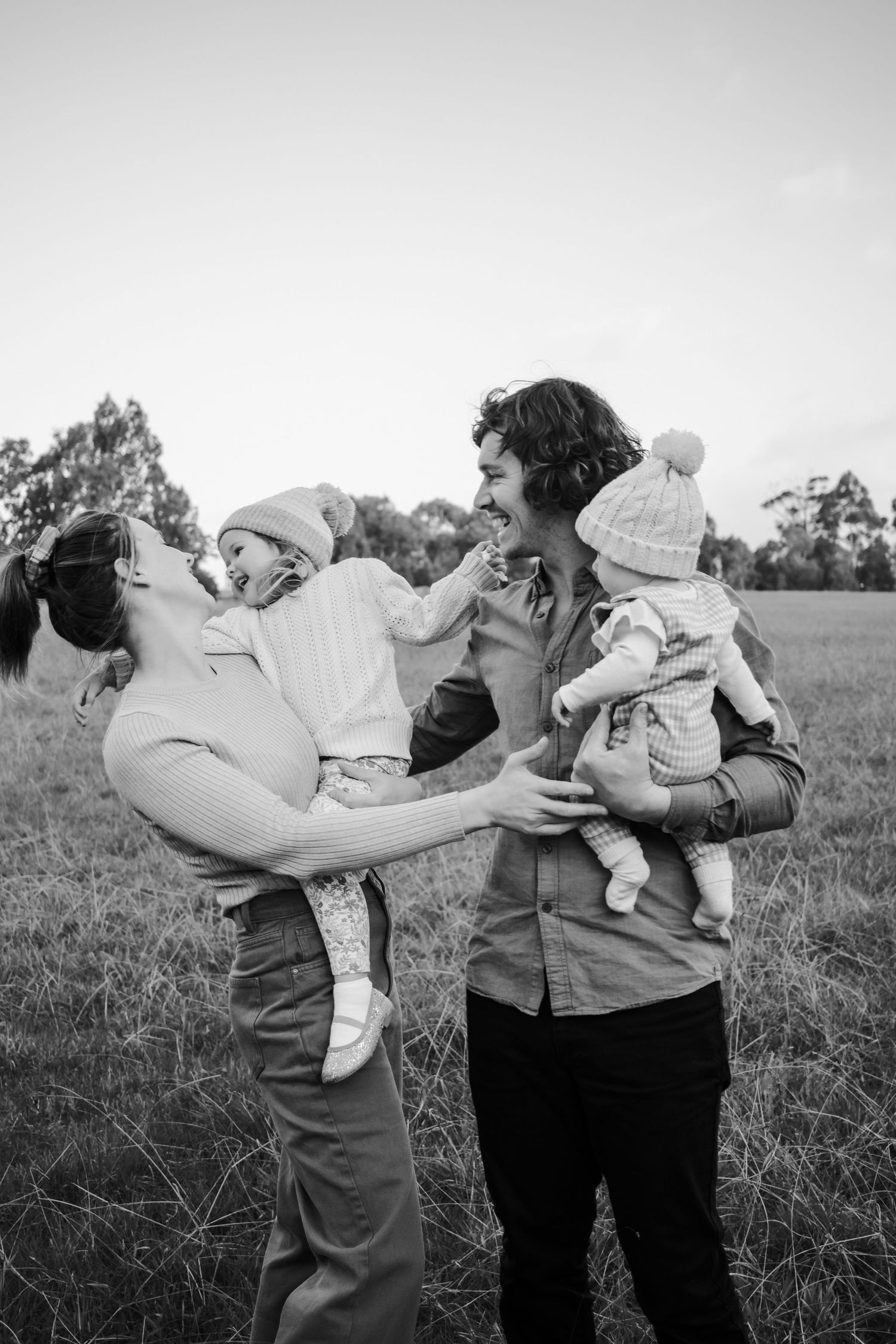 Mum and dad holding their daughers laughing.