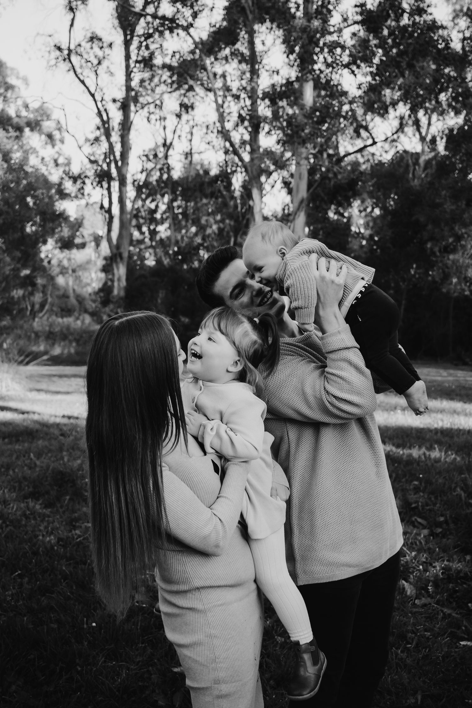Mum and dad holding their children laughing.