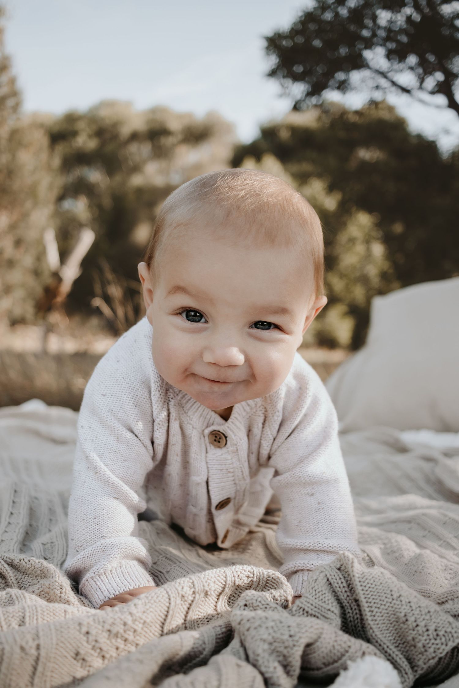 Baby boy on his stomach smiling at the camera.