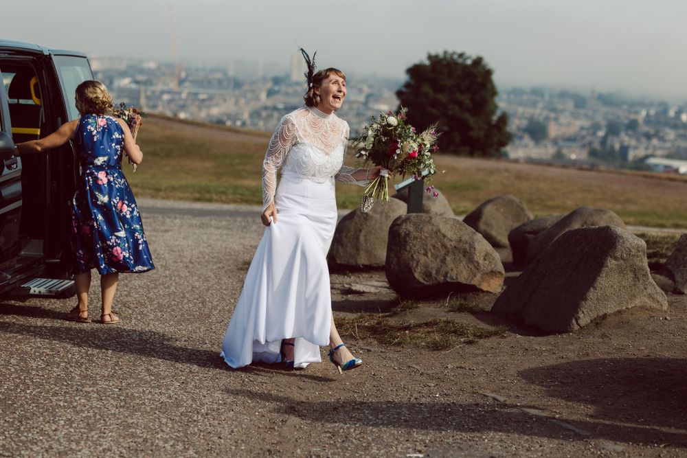 Wedding celebration on hilltop overlooking cityscape with natural rock formations.